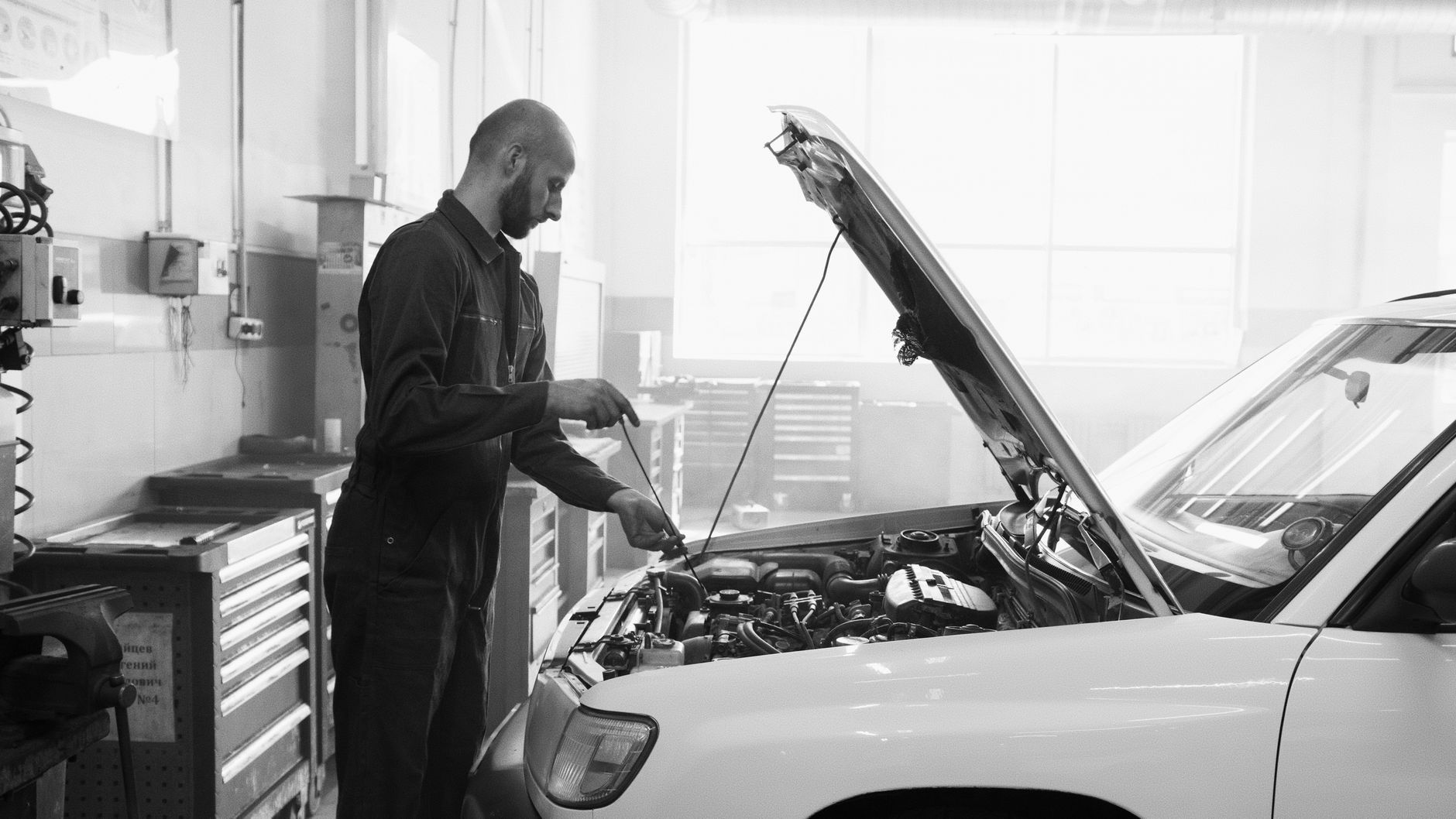 Mechanic inspecting a car engine with the hood raised in a garage