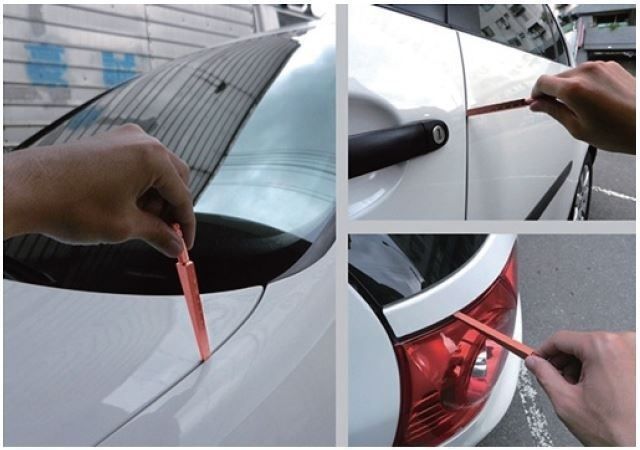Hand checking gaps around a white car with a red tool